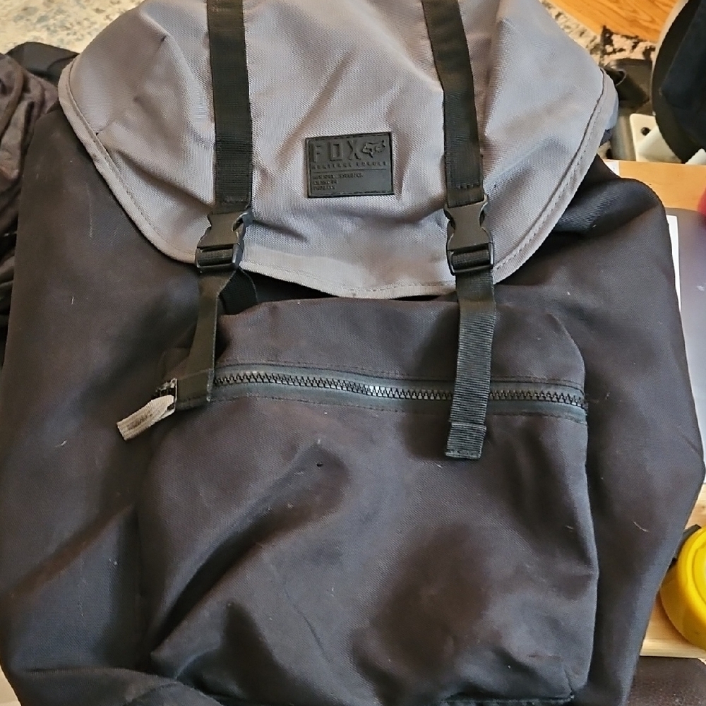 FOX Racing black & gray backpack featuring a top flap secured by buckles.
